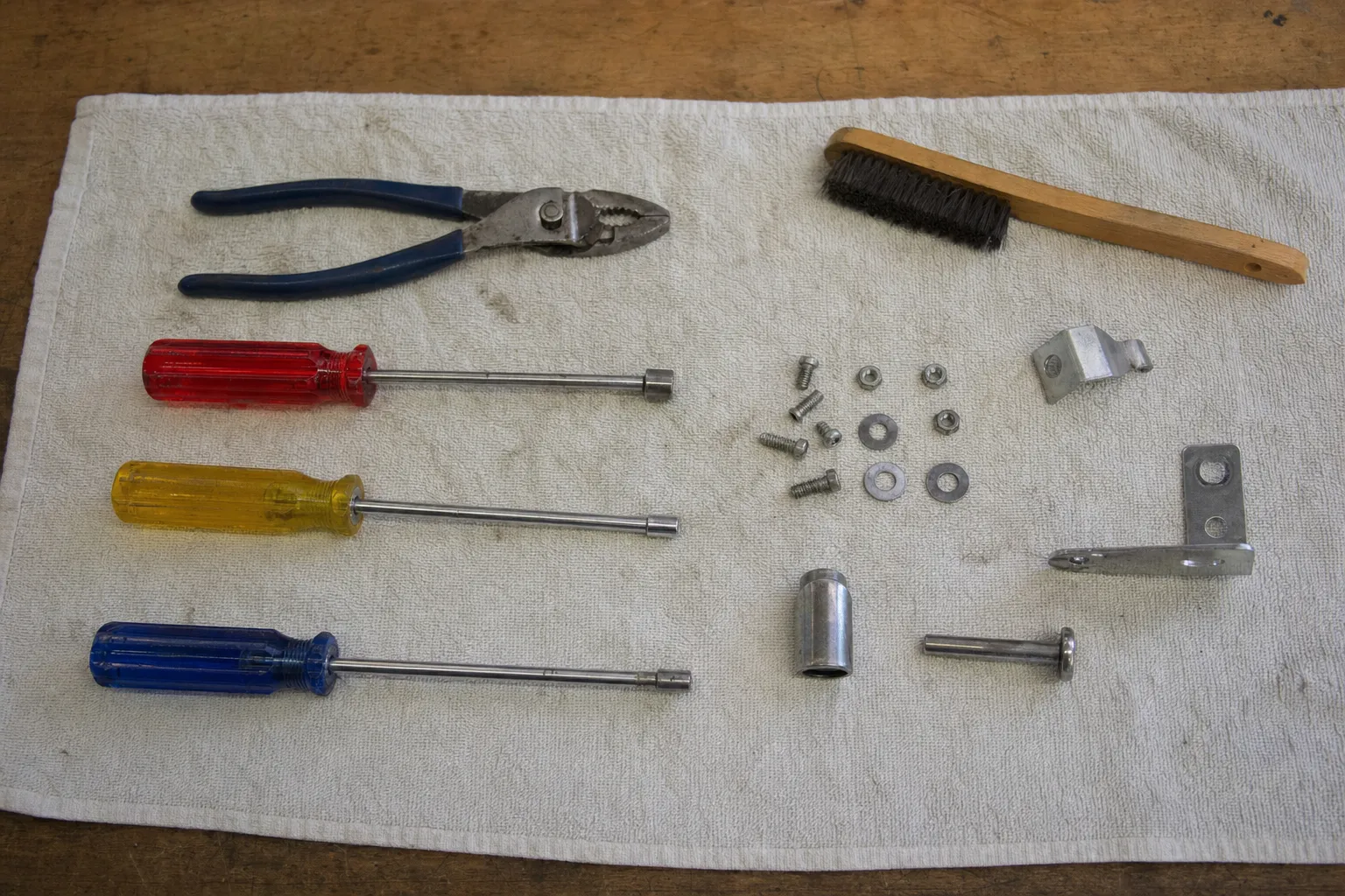 Pliers, screwdrivers, a wire brush, brackets and assorted fixings laid out on a cloth